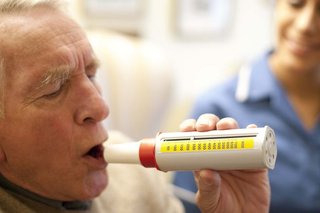 A man about to blow into a tube called a peak flow meter. There’s a numbered scale on the side to measure how fast he can breathe out.